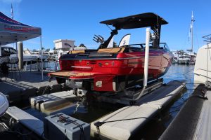 Red wake boat sitting on a Sunstream hydraulic boat lift in a calm water marina.