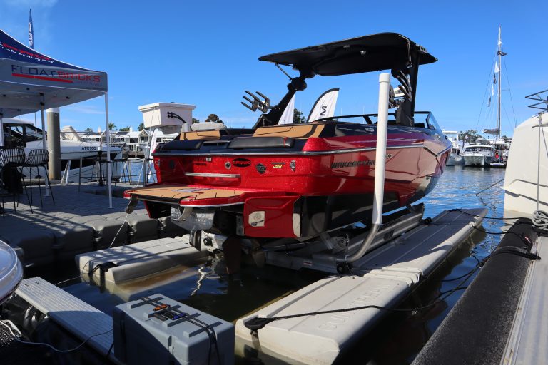 Red wake boat sitting on a Sunstream hydraulic boat lift in a calm water marina.